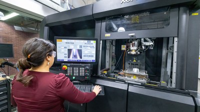 A grad student using a metal 3D printer in Brinkman Machine Tools and Manufacturing Lab