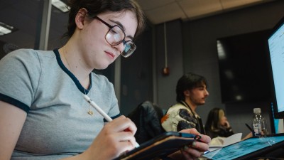 A student draws on a tablet in a computer lab.