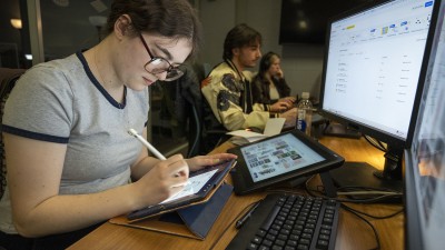 A student draws on a Cintiq while a window on their computer is open.