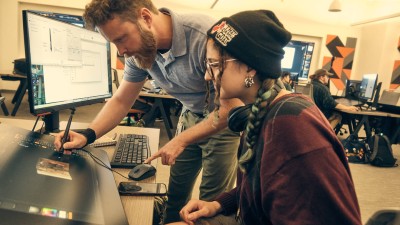 professor helps a student at her work station.