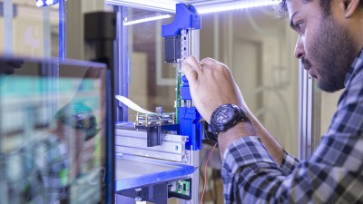 A close up of a student working with a machine in the AMPrint Center.