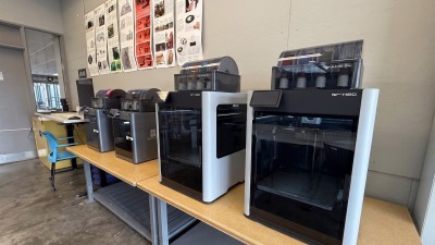 A row of 3D printers in a studio space.
