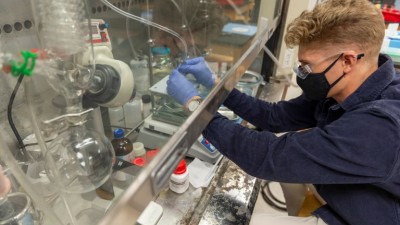 Student with gloves working with lab equipment.