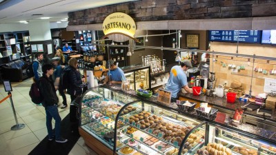 Customers in line next to clear storage racks showing off baked goods.