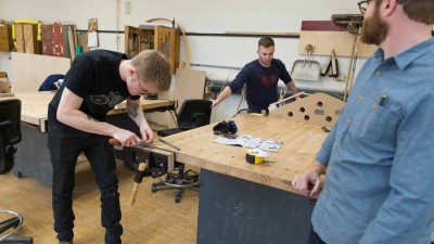 Student sharpening a saw in the bench room.