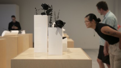 Gallery visitors in City Art Space look at art pieces on pedestals.