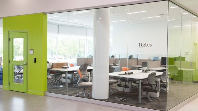 Glass room with lime-green door and several workstations with tables and chairs