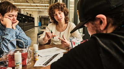 Three students collaborate at a table in the industrial design studio.