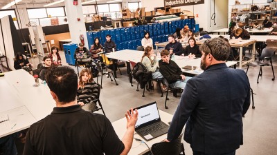 Two guest lecturers speak to industrial design students in the studio.