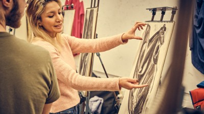 Faculty Nava Barenji talks to a student about their drawing.