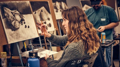A student looks at their drawing.