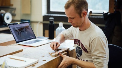 student works on the detail carving of a piece of wood.