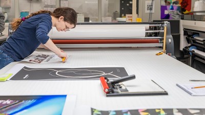 A student cuts a photo print on a table.