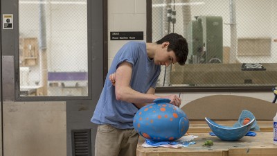 A student paints a furniture design project.