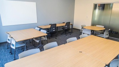 a conference room with tables and chairs, and a whiteboard.