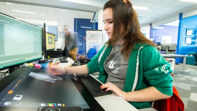 a student draws on a tablet, and her hand is blurry from the motion.