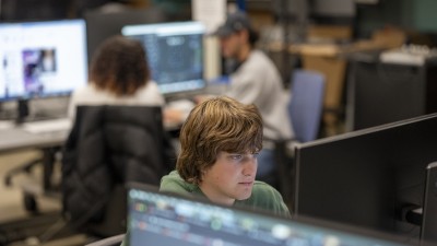 A student works at a computer, with a blurred background.