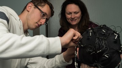 student researcher adjusts a cap with electrodes on a subject.