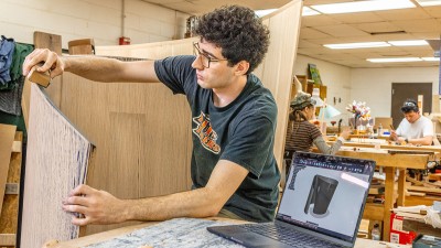 An RIT furniture design student sands an art piece.