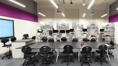 A laboratory with a large table, chairs, and computers.
