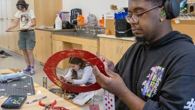 a student works on a cardboard project in a large workspace.