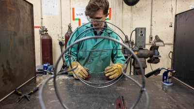 student shapes wires into a sculpture.