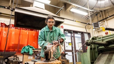 a student uses a grinder on a piece of metal, causing sparks.