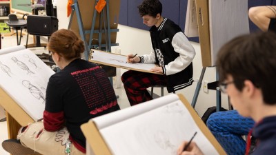 students work on their drawing at desks.