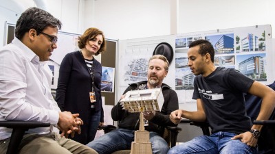 Students and teachers discussing architectural models.