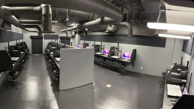 a wide view of the studio, with industrial piping in the ceiling and several individual work stations.
