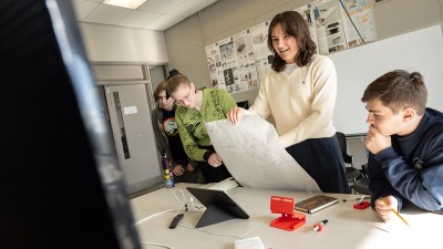 Students smile while working in a studio setting.
