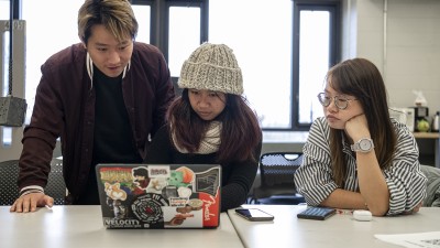 Students huddled around a computer to look at the screen.