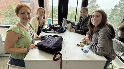 Four smiling students work at a table together.