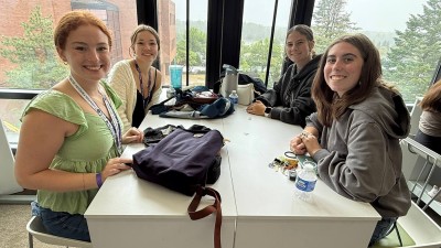 Four smiling students work at a table together.