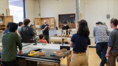 faculty member leads a discussion in a wood shop.