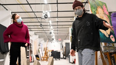 a visiting artist listens as a student describes his work during a critique.