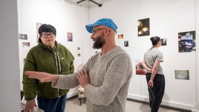 a professor talks to a student while gesturing to a piece of work.