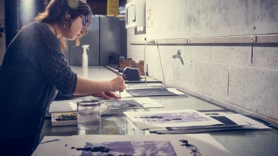 A student spreads out a number of prints on a large surface.