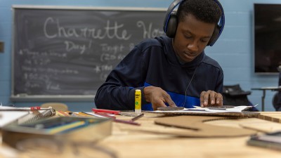 A student glues two cardboard pieces together.
