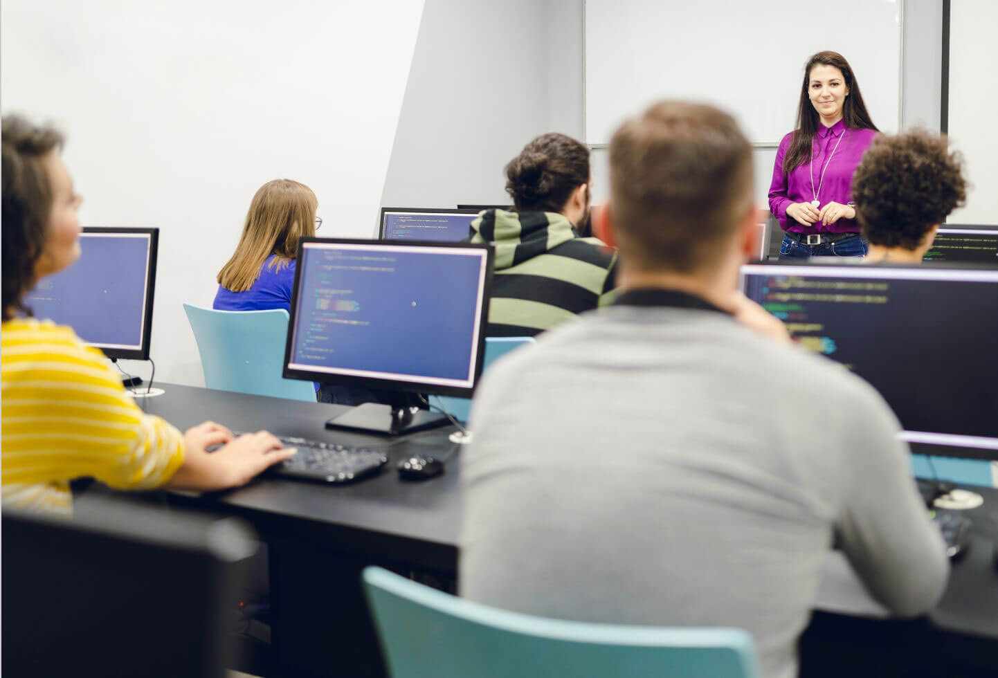 An instructor presenting material to several students at computers.