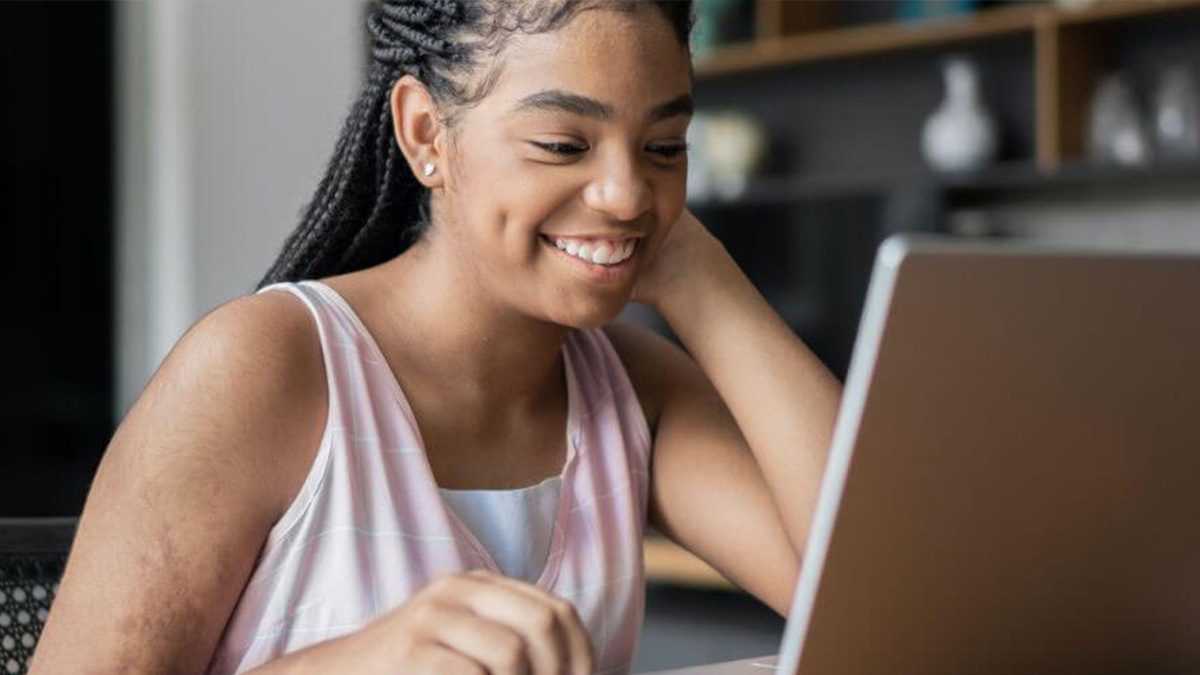 A smiling student working at a computer.