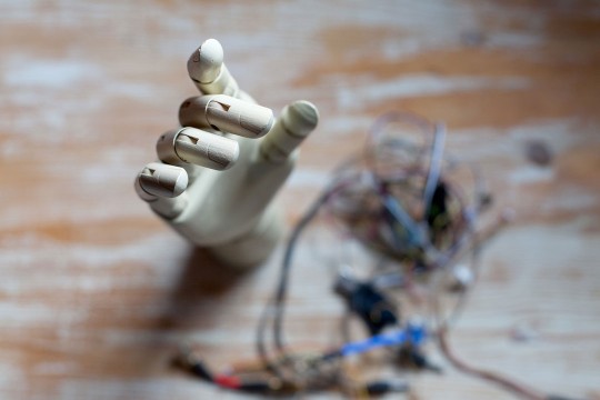 a prosthetic hand sits on a wooden table surrounded by wires