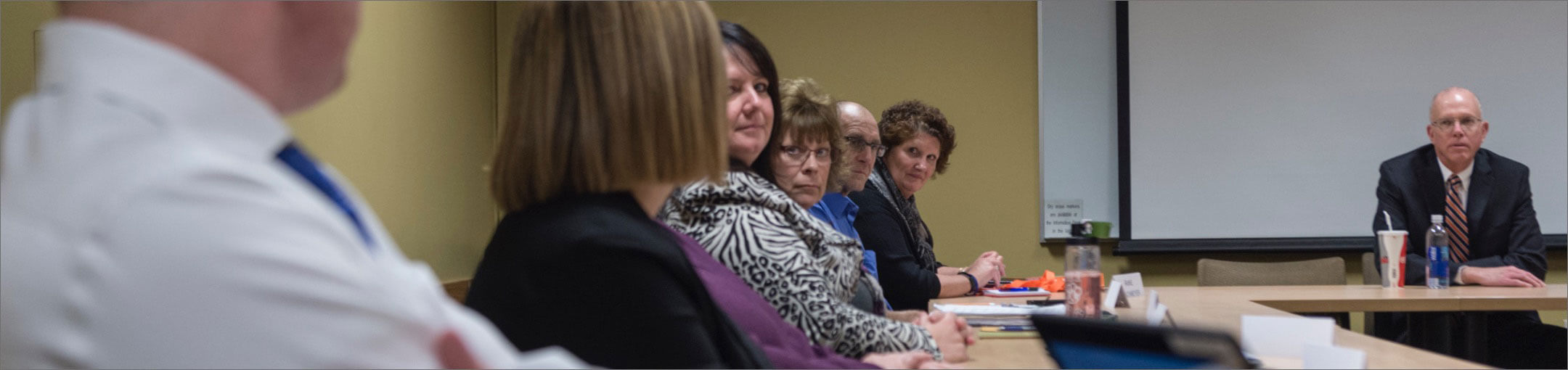 Several members of the R I T Staff Council sitting at a table during a meeting.