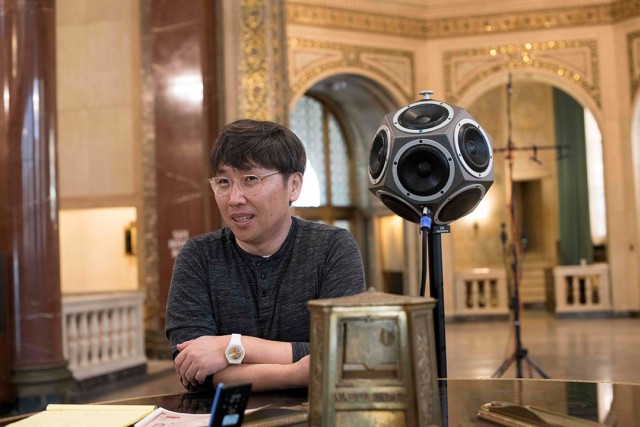 professor standing next to a multfacted speaker.