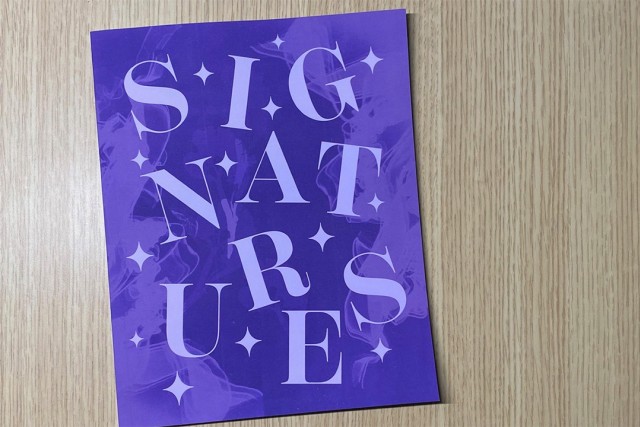 Signatures magazine on a wooden table