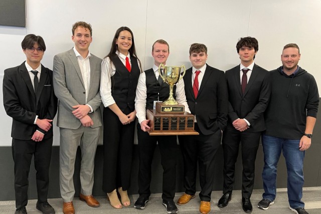The seven person team from Dakota State University is pictured standing with a large trophy.