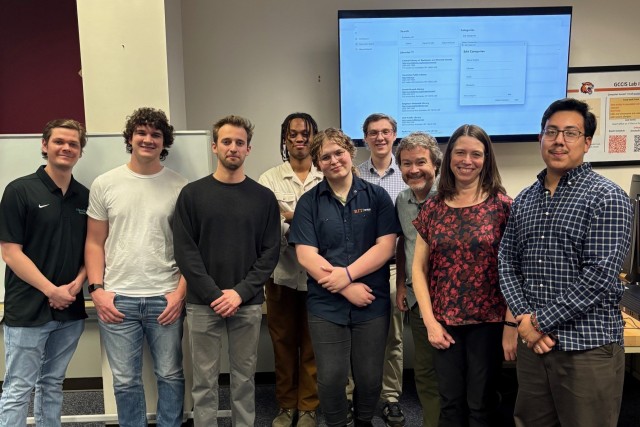 A group of people stand together for a picture in a classroom