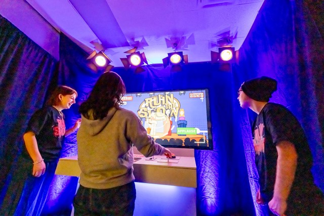 students play a video game in a production room.