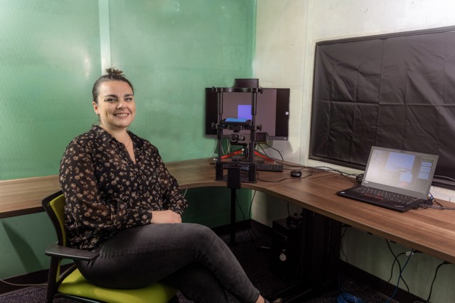 a woman sits at a desk with some equipment and a laptop
