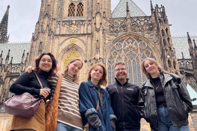 four women and a man stand in front of a building in Prague.
